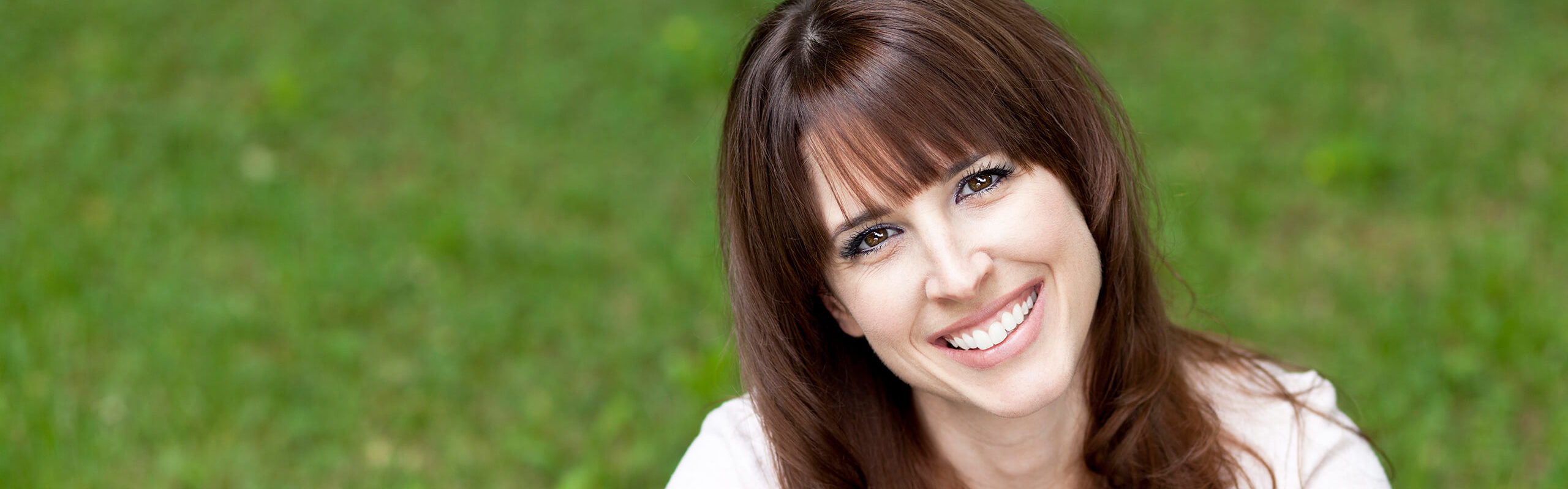 woman sitting in a grassy field, smiling