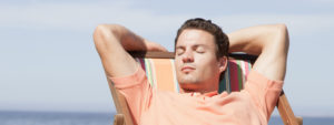 man relaxing with eyes closed in a beach chair