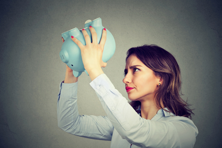 A woman looking in a piggy bank for money